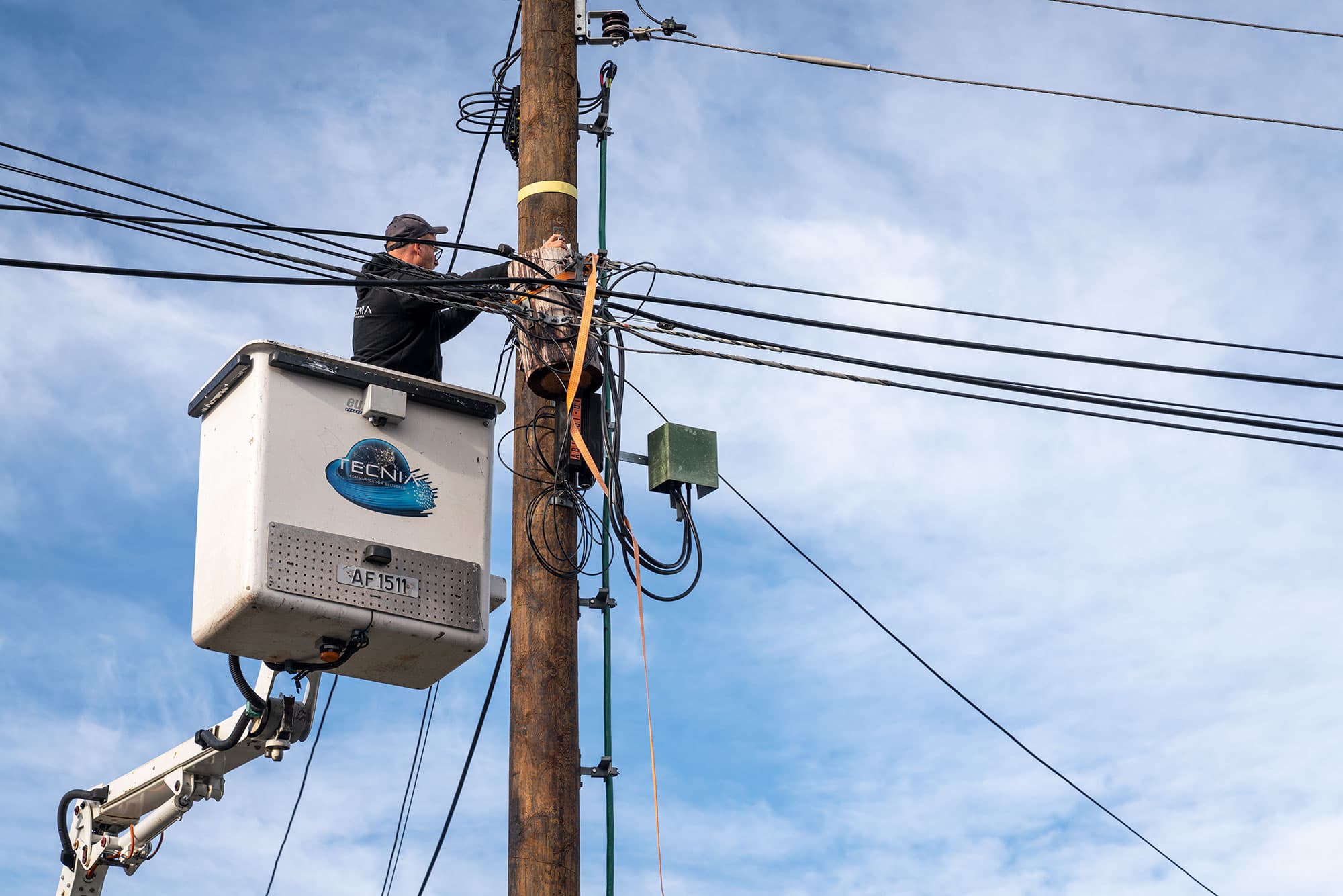 Tecnia AS - Lift ved stolpe med tekniker som utfører fiberinstallasjon
