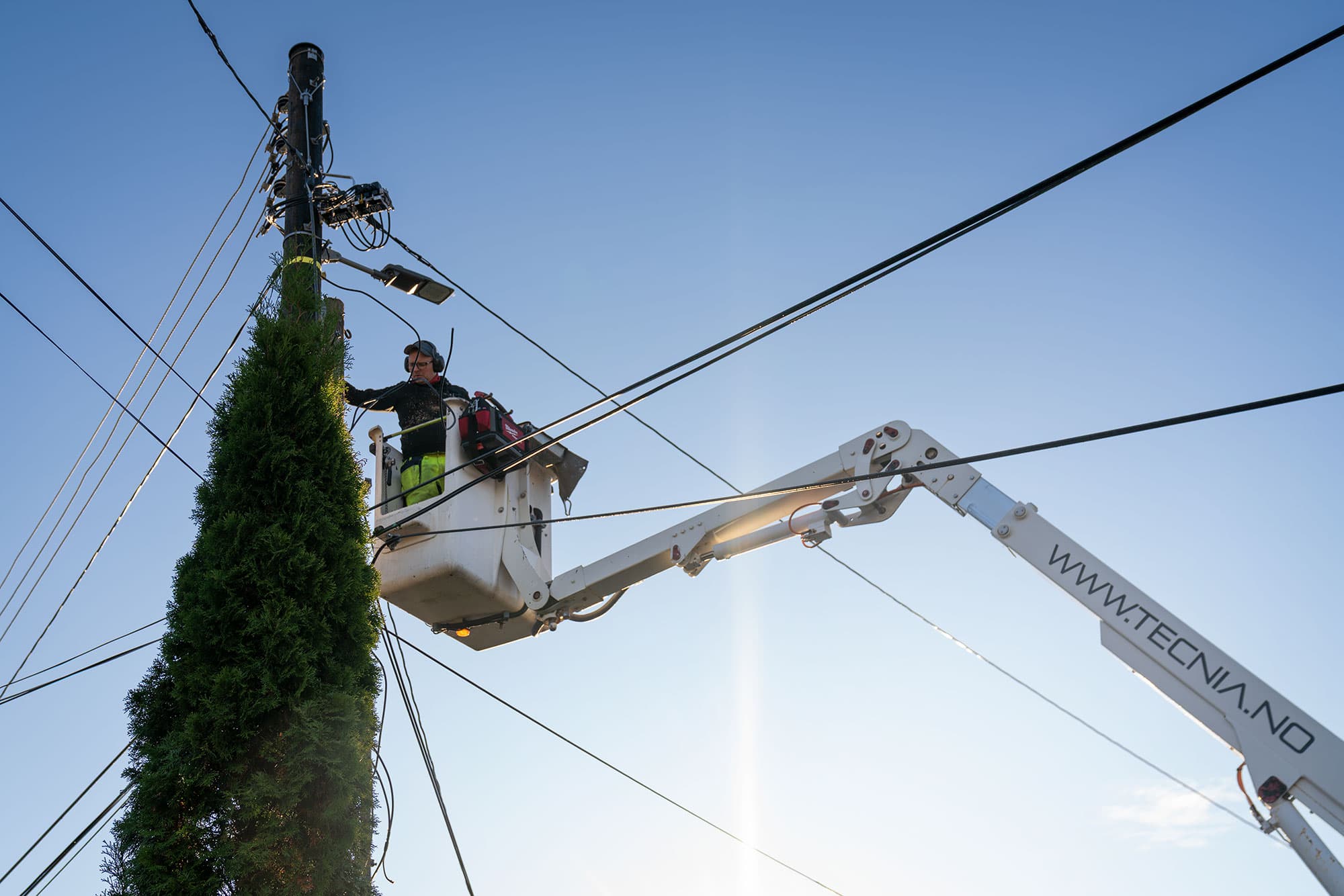 Tecnia AS - Liftarbeid ved telestolpe under blå himmel